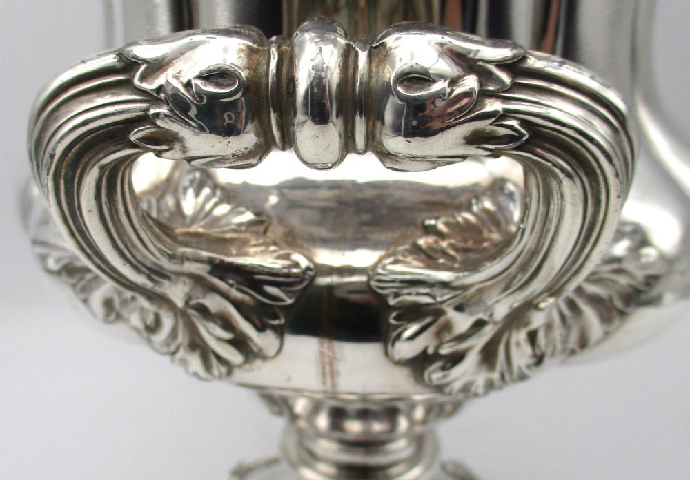 A pair of silver-plated urn-shaped wine coolers featuring scalloped foliate rims, acanthus leaf handles, and flared pedestal bases. View V