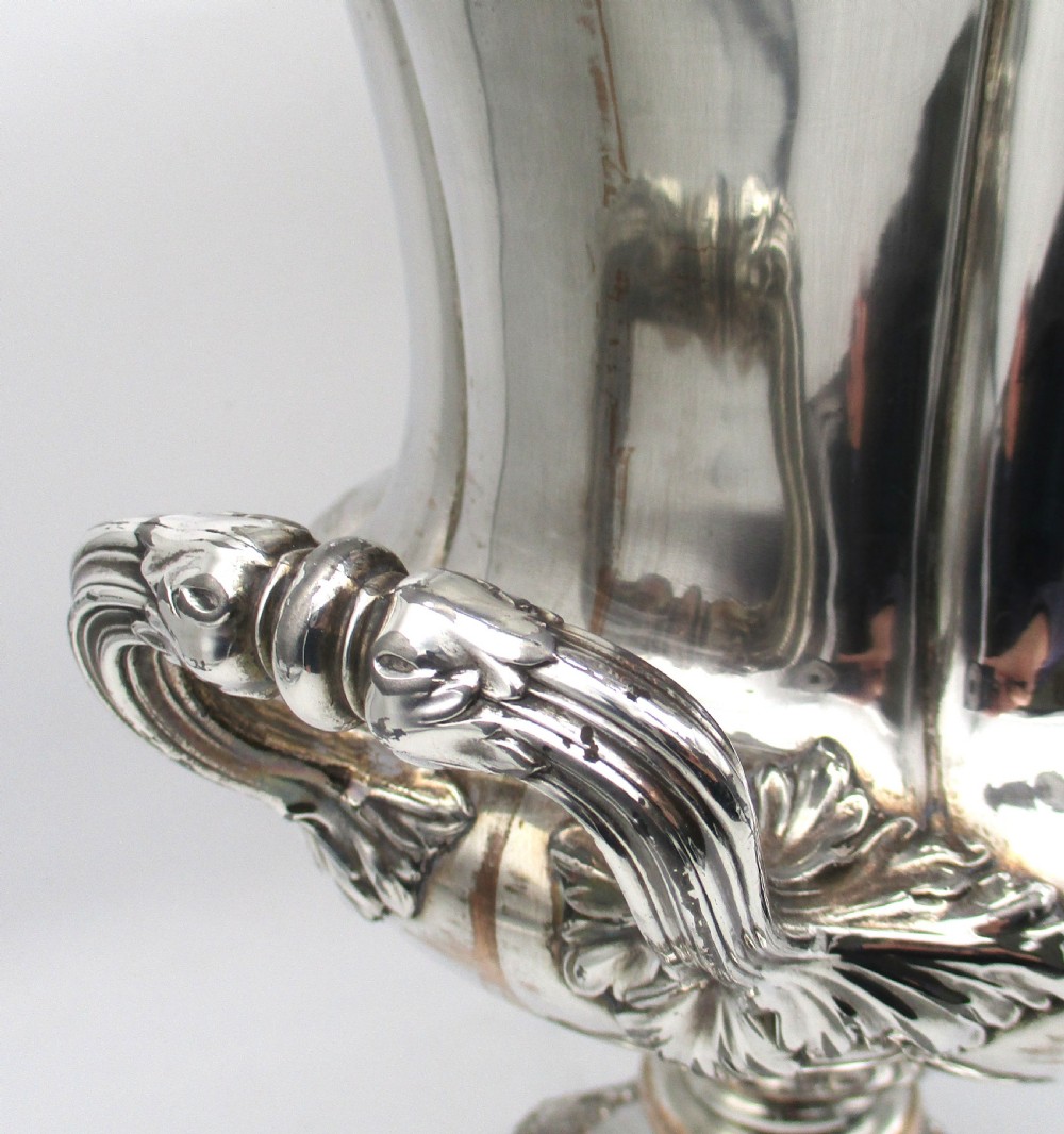 A pair of silver-plated urn-shaped wine coolers featuring scalloped foliate rims, acanthus leaf handles, and flared pedestal bases. View XV