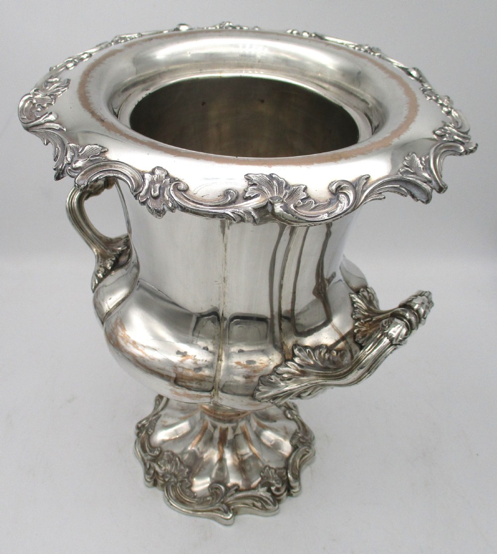 A pair of silver-plated urn-shaped wine coolers featuring scalloped foliate rims, acanthus leaf handles, and flared pedestal bases. View XIX