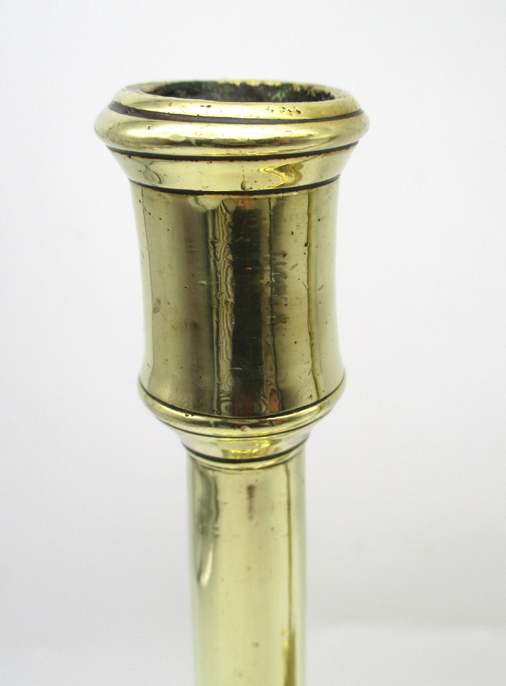A pair of antique brass column candlesticks featuring fluted lower shafts and stepped square bases. View VIII