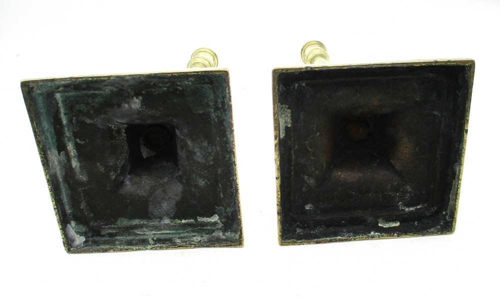 A pair of antique brass column candlesticks featuring fluted lower shafts and stepped square bases. View IX