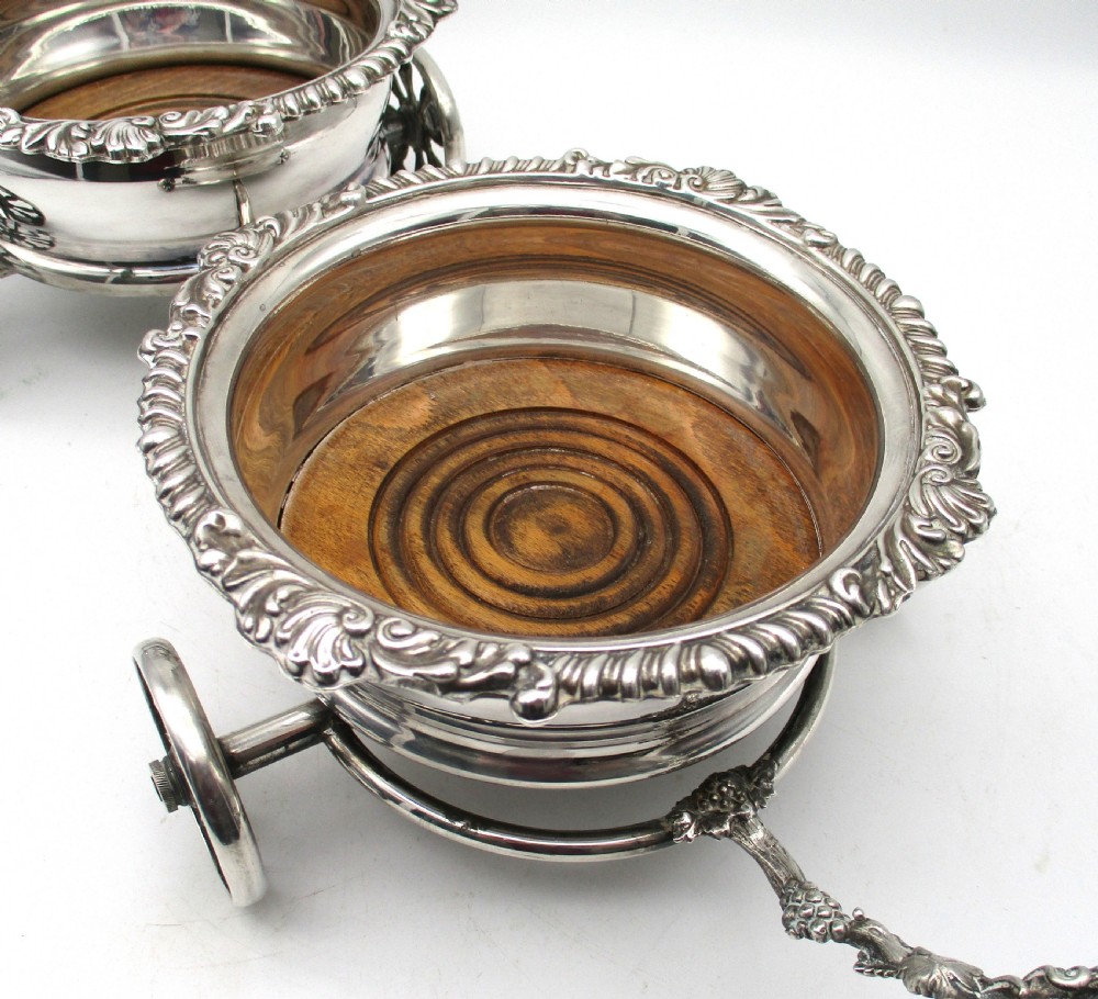 A pair of 19th-century silver-plated decanter coasters mounted on a wheeled carriage trolley with turned wooden bases and a decorative handle. View II