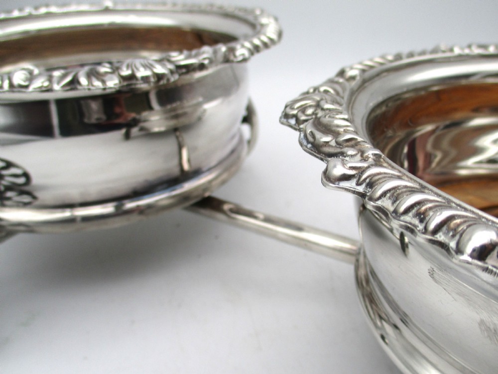 A pair of 19th-century silver-plated decanter coasters mounted on a wheeled carriage trolley with turned wooden bases and a decorative handle. View V