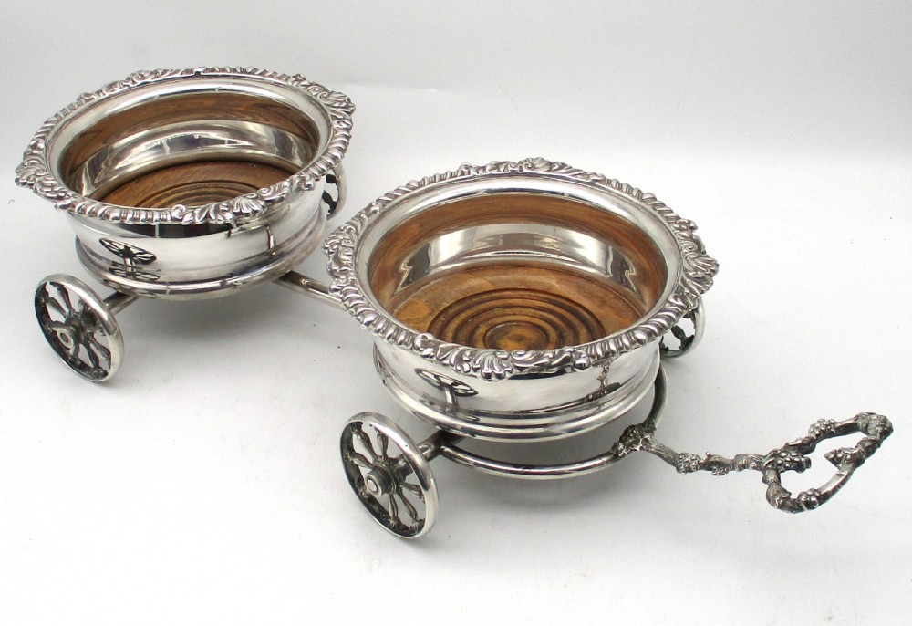 A pair of 19th-century silver-plated decanter coasters mounted on a wheeled carriage trolley with turned wooden bases and a decorative handle. View VI