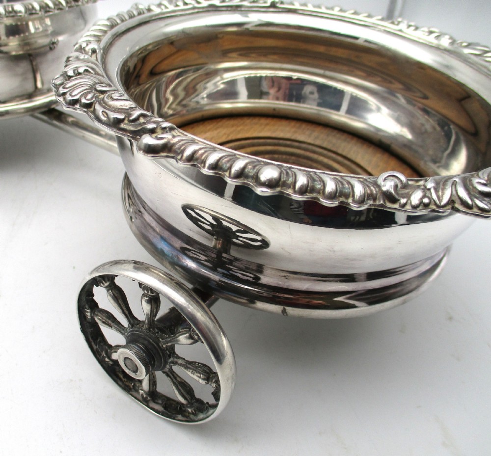 A pair of 19th-century silver-plated decanter coasters mounted on a wheeled carriage trolley with turned wooden bases and a decorative handle. View XIII