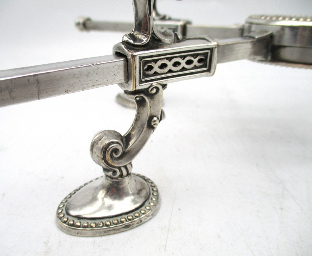 An antique Georgian Sheffield plated silver dish cross featuring four adjustable sliding arms with beaded support pads and feet. View IX