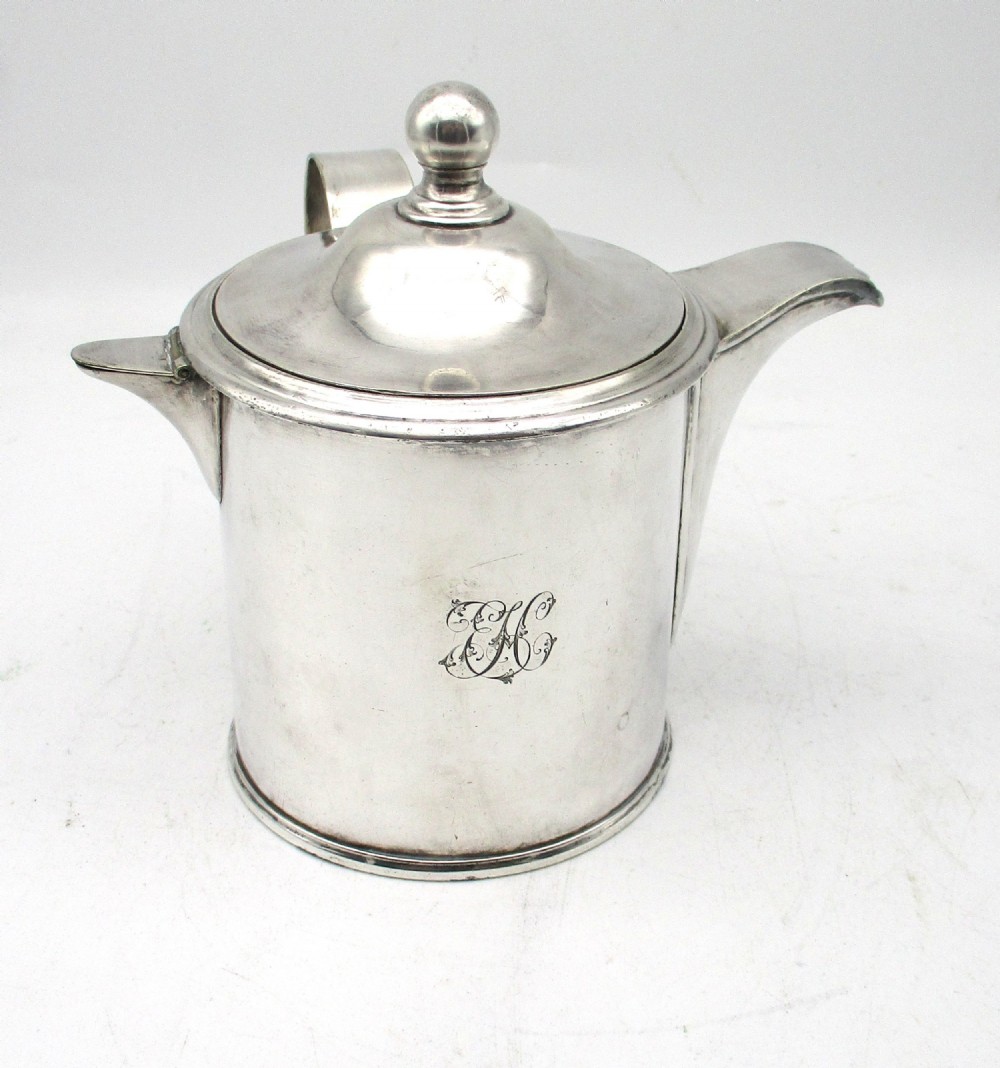 A cylindrical mid 19th-century silver-plated argyll gravy warmer with a rounded lid, ball finial, double spout, handle, and engraved cursive monogram.