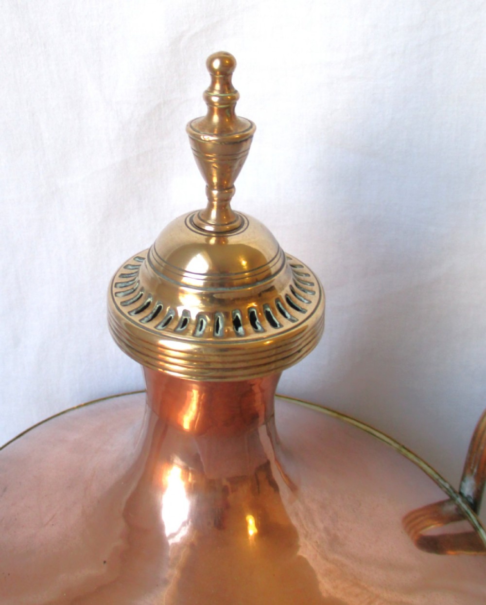 An early nineteenth-century copper tea urn featuring loop handles, a brass spigot, a decorative finial, and a square stepped pedestal base. View III