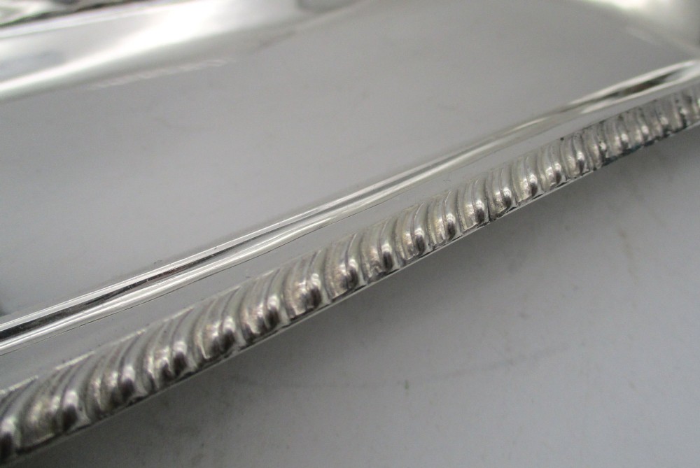 An elongated 19th-century silver-plated knife tray with a gadrooned rope-twist border rim and an engraved motif on the inner wall. View VII