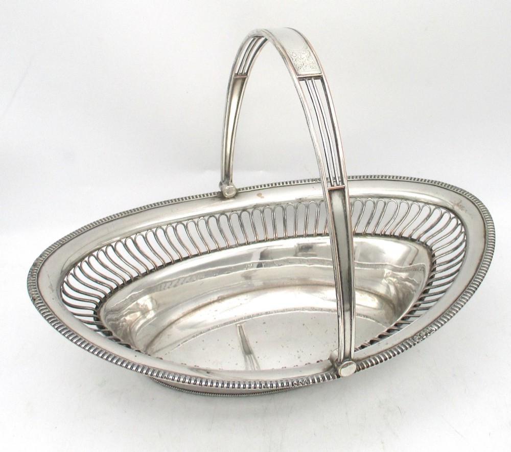 An oval Old Sheffield plate silver basket featuring an openwork wirework gallery, a beaded rim, and an overhead swing handle. View II