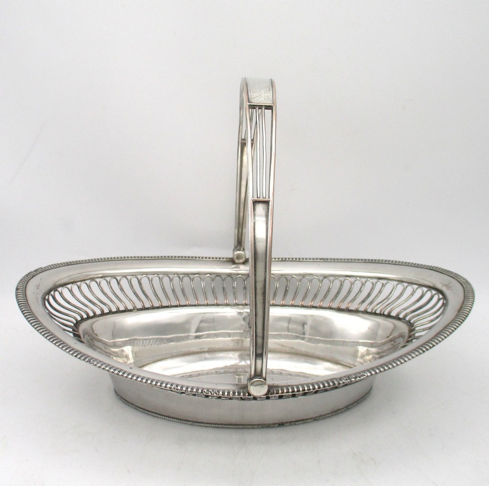 An oval Old Sheffield plate silver basket featuring an openwork wirework gallery, a beaded rim, and an overhead swing handle. View III