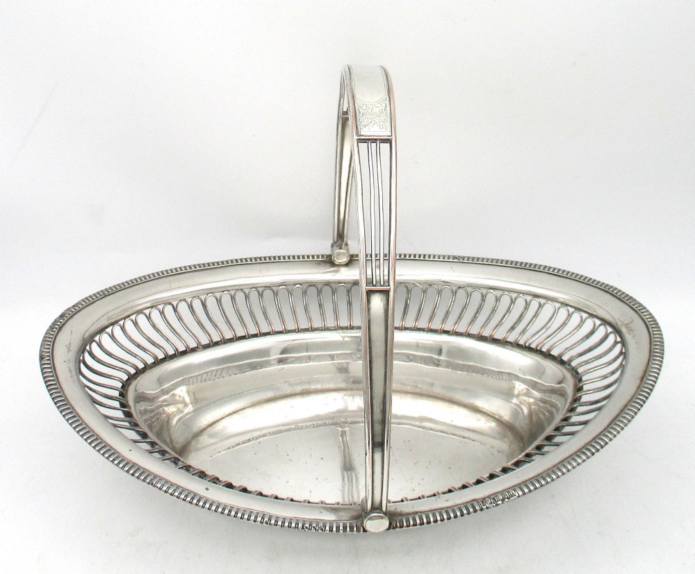 An oval Old Sheffield plate silver basket featuring an openwork wirework gallery, a beaded rim, and an overhead swing handle. View IV