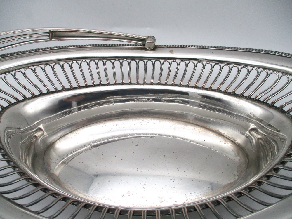 An oval Old Sheffield plate silver basket featuring an openwork wirework gallery, a beaded rim, and an overhead swing handle. View VII