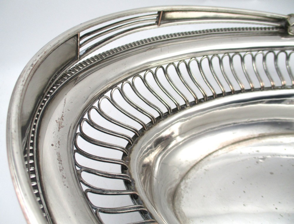 An oval Old Sheffield plate silver basket featuring an openwork wirework gallery, a beaded rim, and an overhead swing handle. View VIII