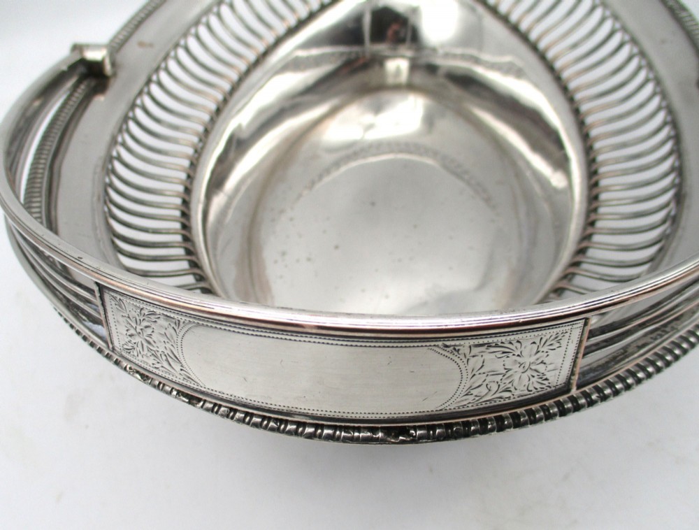 An oval Old Sheffield plate silver basket featuring an openwork wirework gallery, a beaded rim, and an overhead swing handle. View IX
