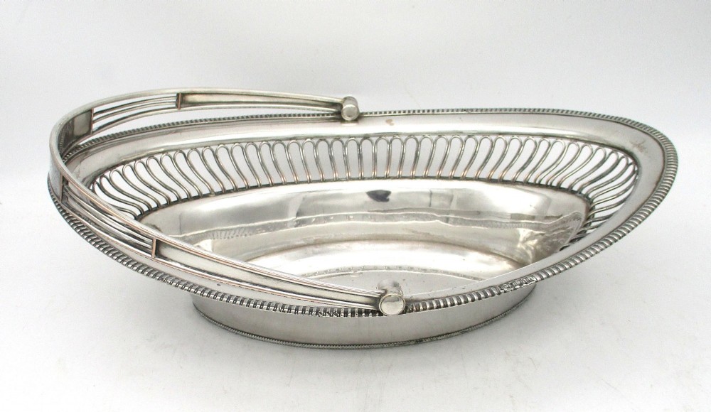 An oval Old Sheffield plate silver basket featuring an openwork wirework gallery, a beaded rim, and an overhead swing handle. View XI