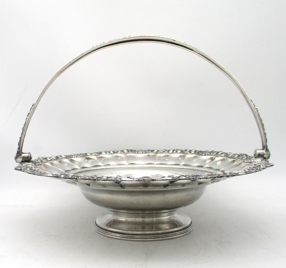 A round Old Sheffield Plate silver basket with a fluted rim, shell border motifs, an engraved crest, and a overhead swing handle. View III