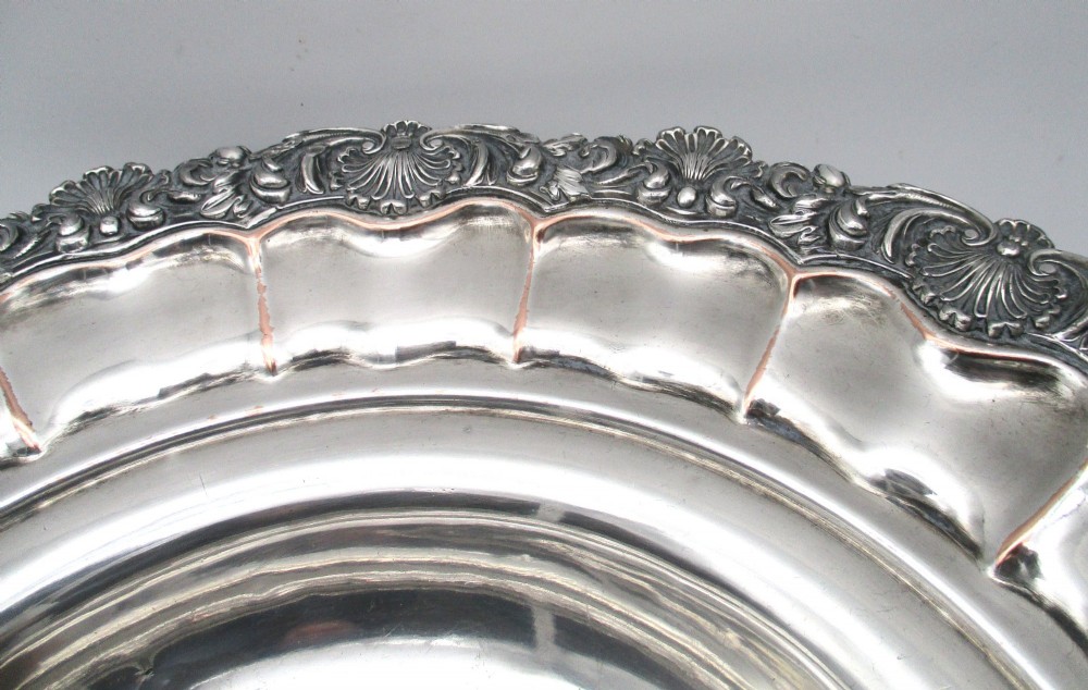 A round Old Sheffield Plate silver basket with a fluted rim, shell border motifs, an engraved crest, and a overhead swing handle. View VIII