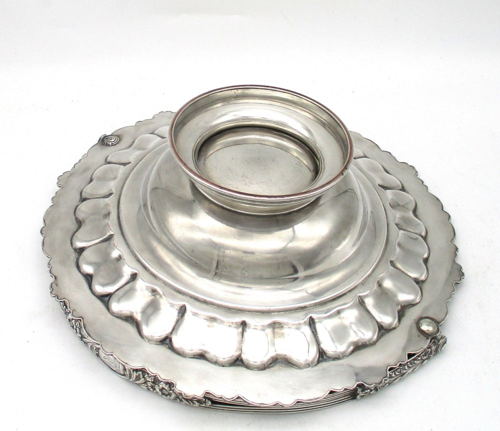 A round Old Sheffield Plate silver basket with a fluted rim, shell border motifs, an engraved crest, and a overhead swing handle. View IX