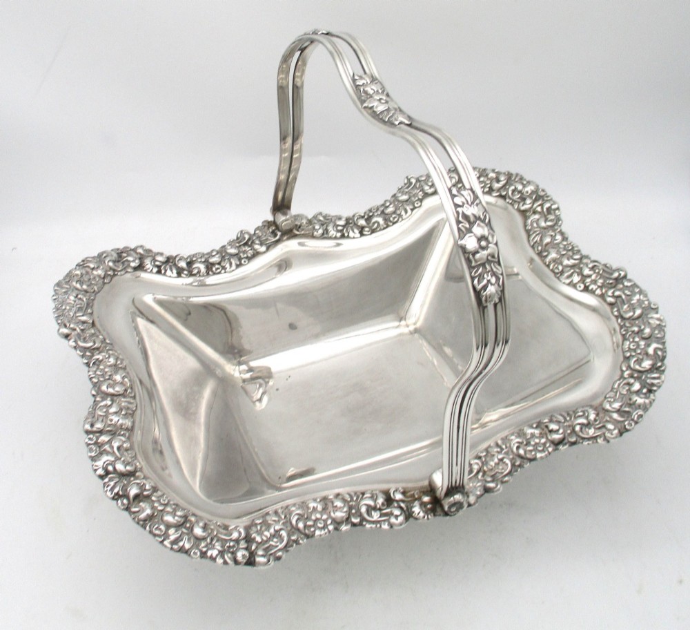 A Regency silver-plated fruit basket featuring a lobed rim with embossed floral motifs and a hinged overhead handle.
