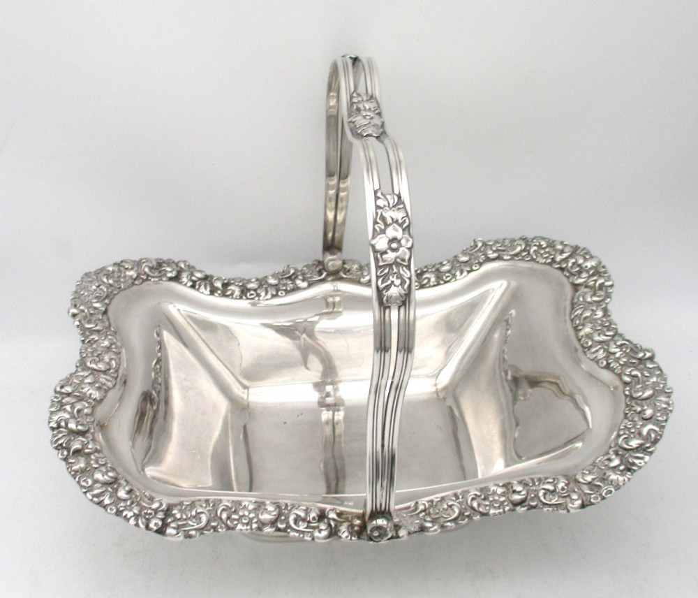 A Regency silver-plated fruit basket featuring a lobed rim with embossed floral motifs and a hinged overhead handle. View III