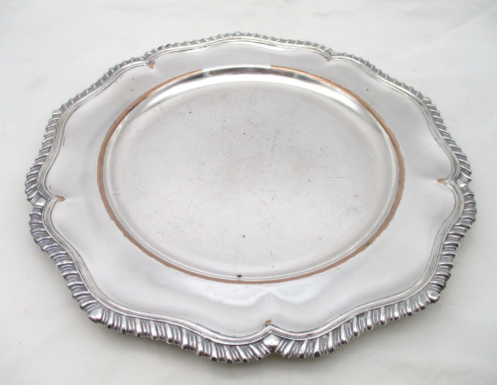 A stack of silver-plated dinner plates displaying scalloped, gadrooned borders with subtle copper show-through along the inner rims. View VIII