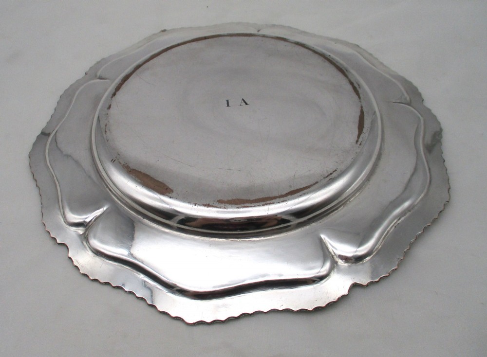 A stack of silver-plated dinner plates displaying scalloped, gadrooned borders with subtle copper show-through along the inner rims. View XI