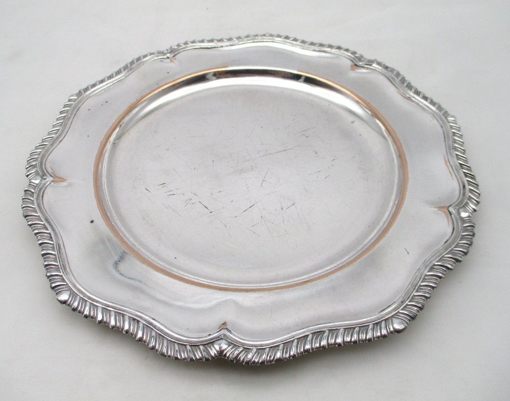 A stack of silver-plated dinner plates displaying scalloped, gadrooned borders with subtle copper show-through along the inner rims. View XIII