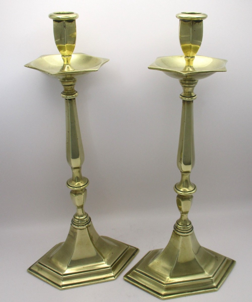 A pair of tall antique brass church candlesticks featuring faceted stems, hexagonal drip pans, and stepped hexagonal bases. View II