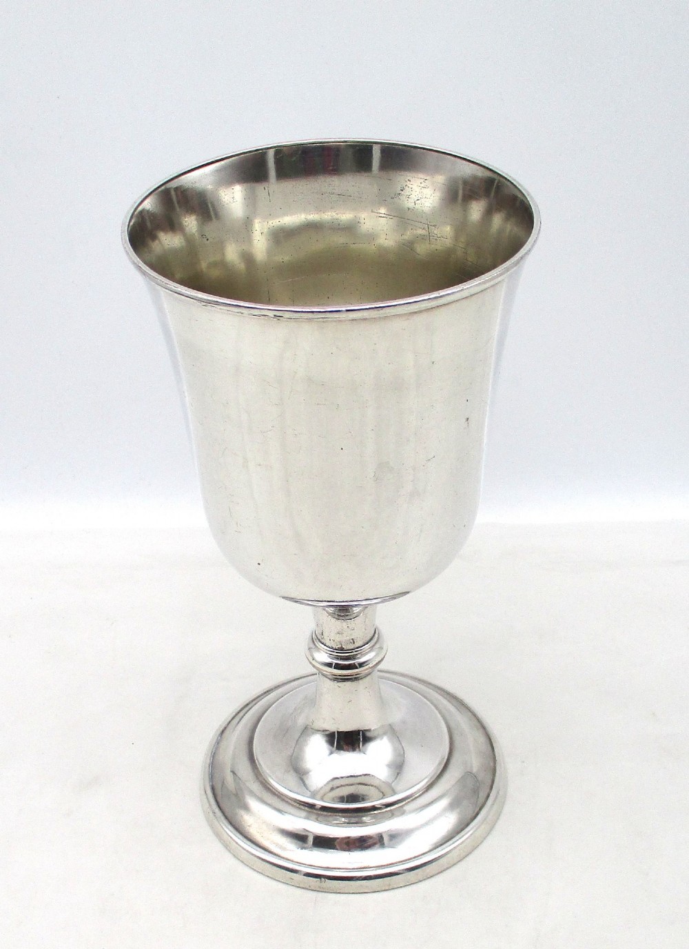 A 19th-century silver-plated church chalice featuring a flared cup with an engraved IHS Christogram medallion, a knopped stem, and a stepped circular base. View VI
