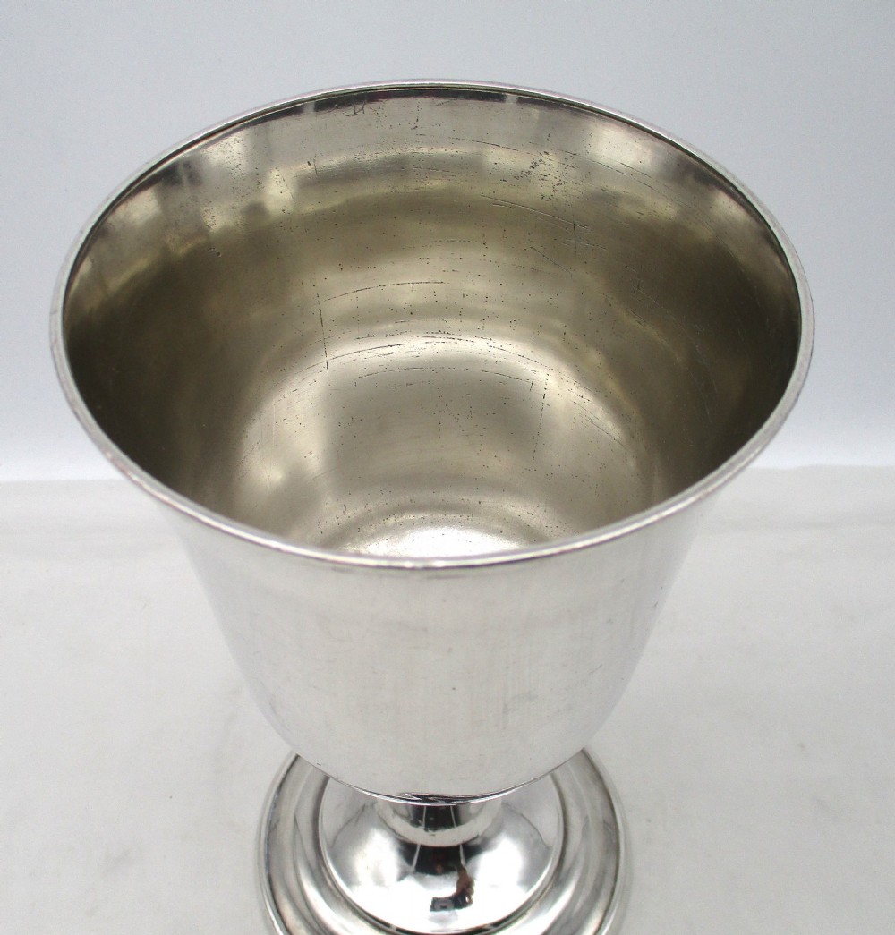A 19th-century silver-plated church chalice featuring a flared cup with an engraved IHS Christogram medallion, a knopped stem, and a stepped circular base. View VII