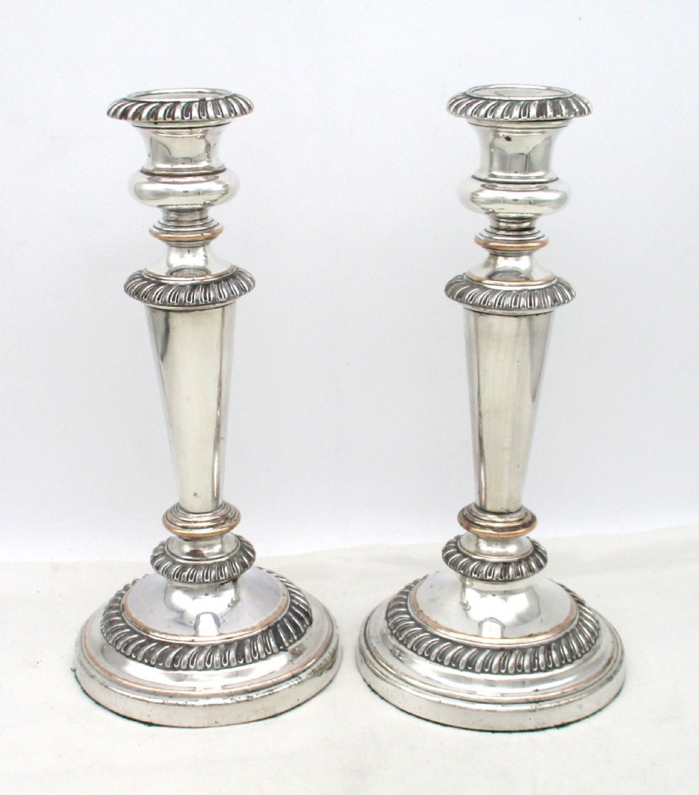 A pair of antique silver-plated candlesticks featuring gadrooned borders, tapered central stems, and circular bases. View III