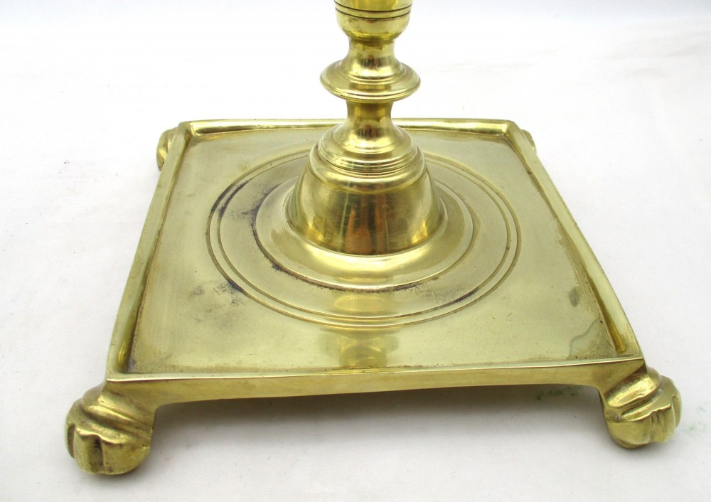 A pair of polished brass candlesticks with turned baluster stems and square bases featuring corner feet. View IV