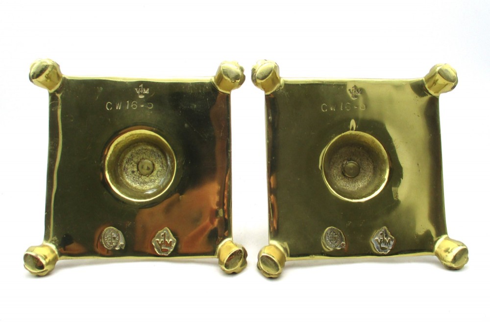 A pair of polished brass candlesticks with turned baluster stems and square bases featuring corner feet. View VI