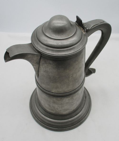 A pair of matching 19th-century pewter communion flagons featuring domed hinged lids, thumbpiece levers, scroll handles, and engraved inscriptions on the cylindrical bodies. View XI