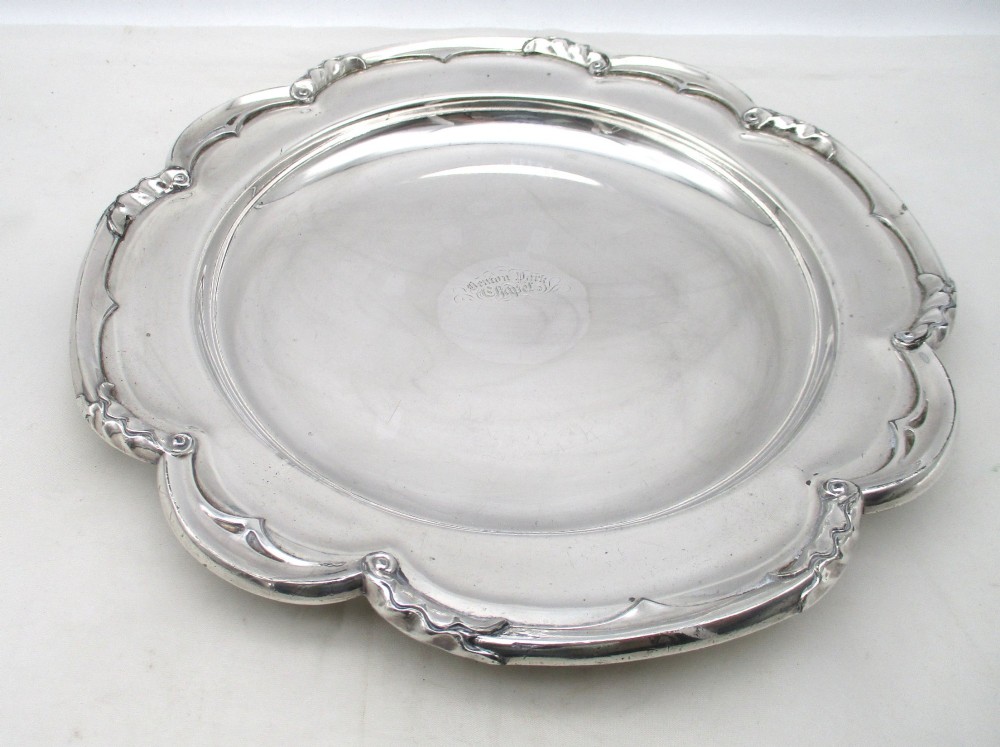 A pair of silver-plated communion plates featuring shaped scalloped rims with decorative relief detailing and engraved central crests. View II