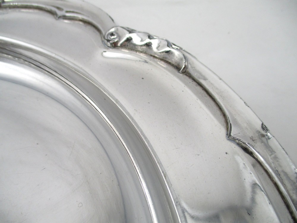 A pair of silver-plated communion plates featuring shaped scalloped rims with decorative relief detailing and engraved central crests. View IV