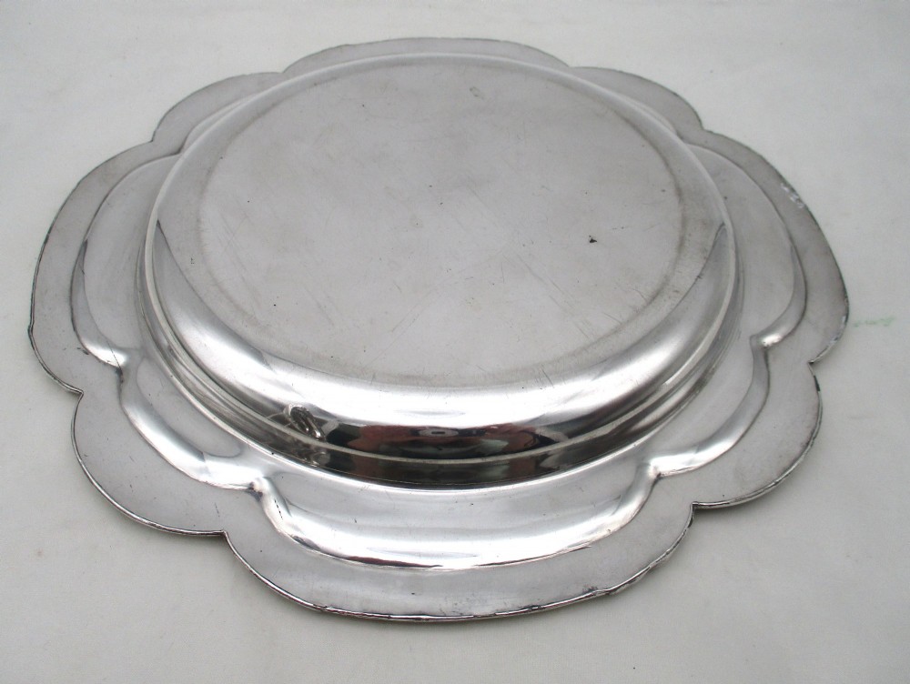 A pair of silver-plated communion plates featuring shaped scalloped rims with decorative relief detailing and engraved central crests. View V