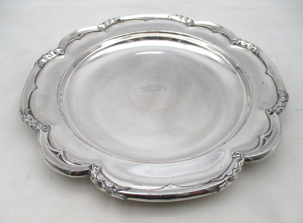 A pair of silver-plated communion plates featuring shaped scalloped rims with decorative relief detailing and engraved central crests. View VI