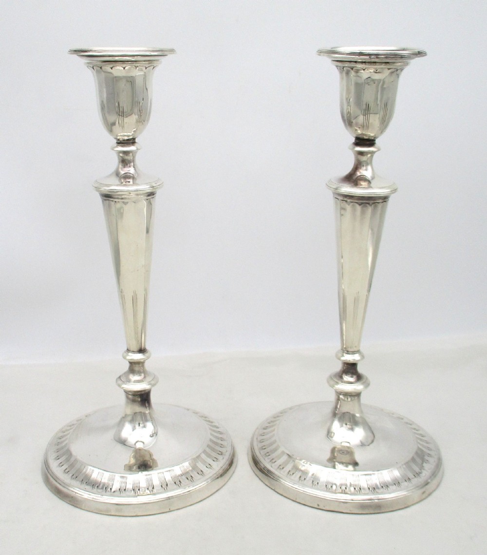 A pair of 19th-century silver-plated candlesticks featuring fluted tapered stems, urn-form sconces, and circular stepped bases. View II