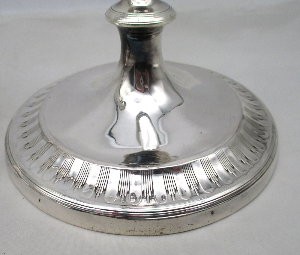 A pair of 19th-century silver-plated candlesticks featuring fluted tapered stems, urn-form sconces, and circular stepped bases. View V