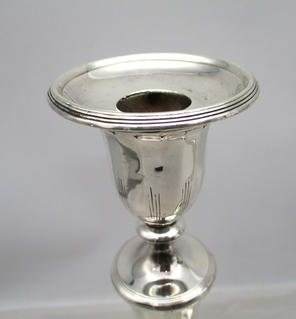 A pair of 19th-century silver-plated candlesticks featuring fluted tapered stems, urn-form sconces, and circular stepped bases. View VI