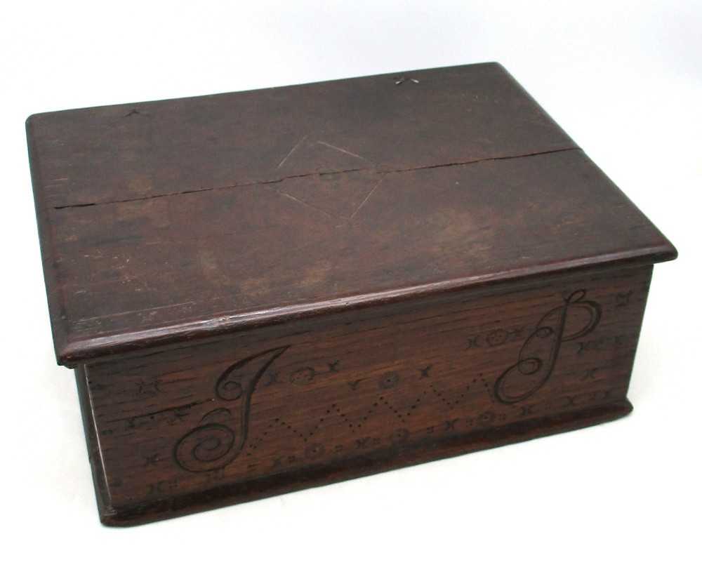 A rectangular dark oak document box featuring carved initials and geometric chip-carved detailing across the front panel.