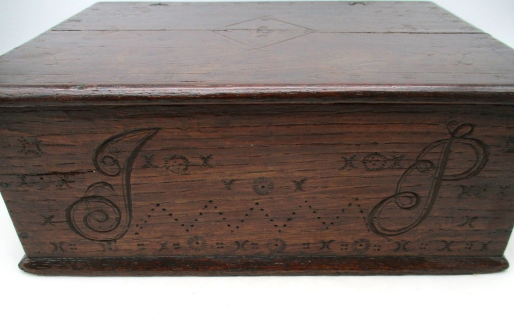 A rectangular dark oak document box featuring carved initials and geometric chip-carved detailing across the front panel. View III