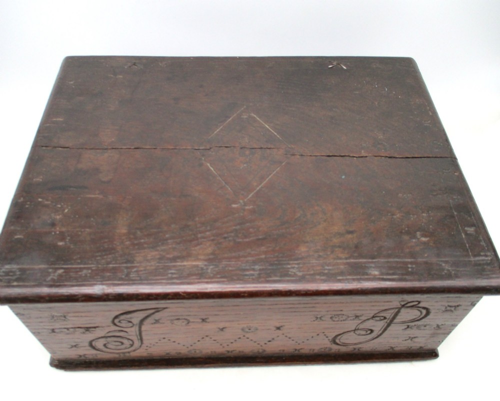 A rectangular dark oak document box featuring carved initials and geometric chip-carved detailing across the front panel. View IV
