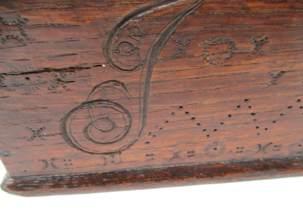 A rectangular dark oak document box featuring carved initials and geometric chip-carved detailing across the front panel. View VII