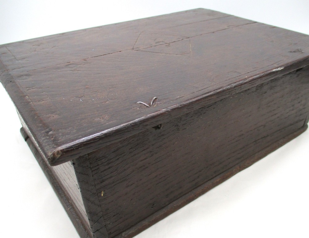 A rectangular dark oak document box featuring carved initials and geometric chip-carved detailing across the front panel. View VIII