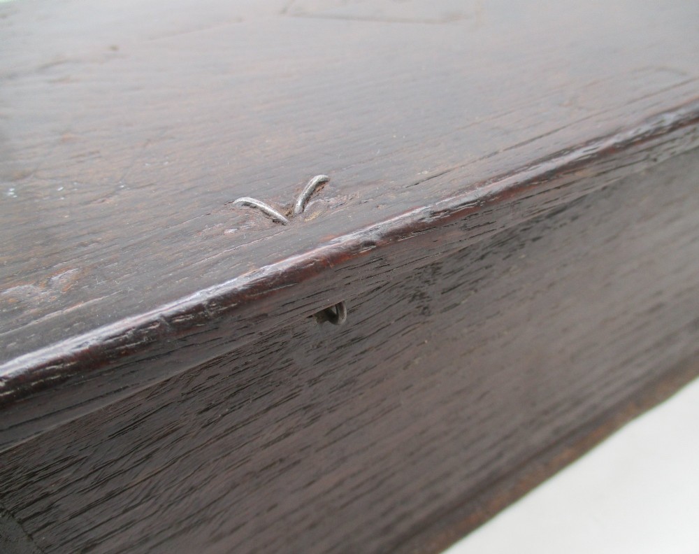 A rectangular dark oak document box featuring carved initials and geometric chip-carved detailing across the front panel. View IX