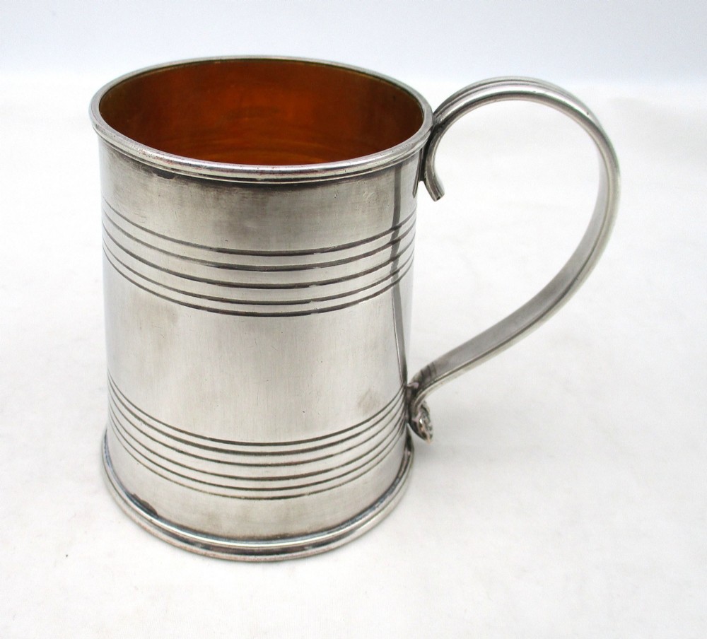 A Regency period Old Sheffield Plate childs tankard featuring horizontal reeded banding, a curved handle, and a gilt-lined interior.