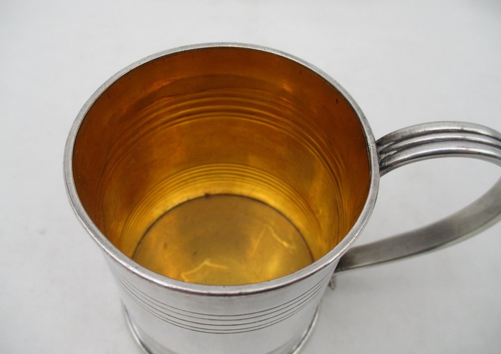 A Regency period Old Sheffield Plate childs tankard featuring horizontal reeded banding, a curved handle, and a gilt-lined interior. View II